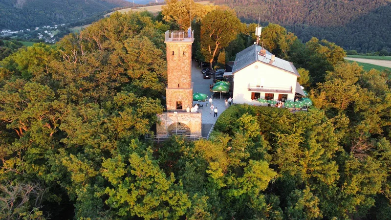 Luftbild von Concordiaturm und Restaurant in der Abendsonne, mit Gästen und Sonnenschirmen auf dem Vorplatz